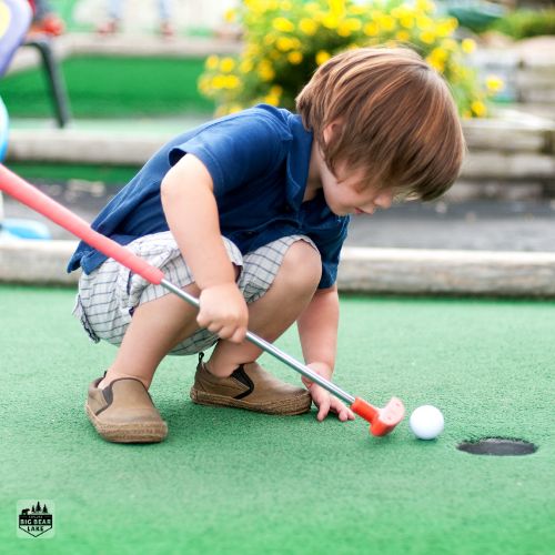 Kid playing mini golf at Alpine slide at magic mountain mini golf course in big bear