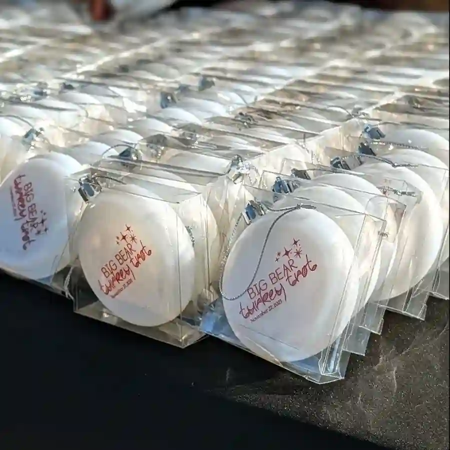 Rows of white Big Bear Turkey Trot finisher ornaments displayed on a table in clear packaging.