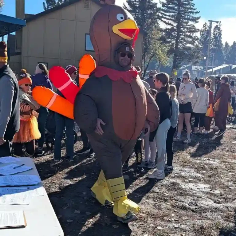 A person wearing a large inflatable turkey costume walks through a crowd of participants at the Big Bear Turkey Trot.