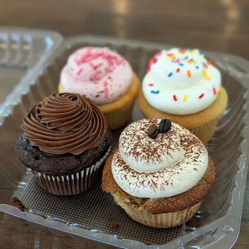 Four assorted cupcakes including chocolate, vanilla, tiramisu, and strawberry at Sister My Sister Bake Shop in Big Bear.