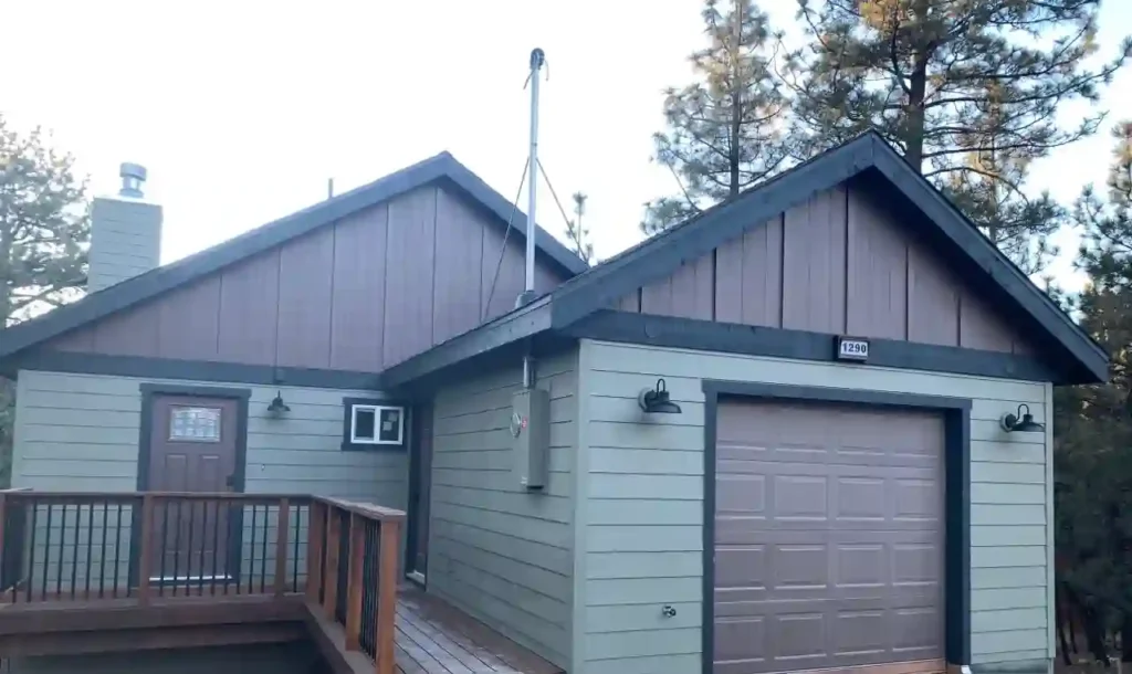 Exterior of Cabin, blue and brown, in Big Bear Lake with one-car garage and pine trees