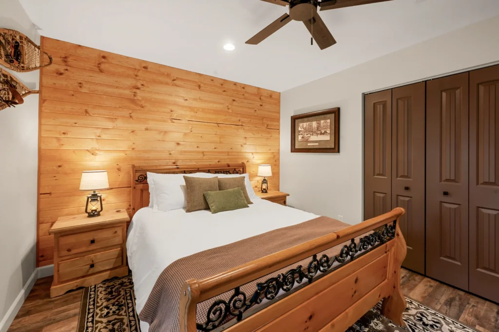 Primary bedroom with Queen bed in Minton Grove Cabin, with warm toned wooden wall in back