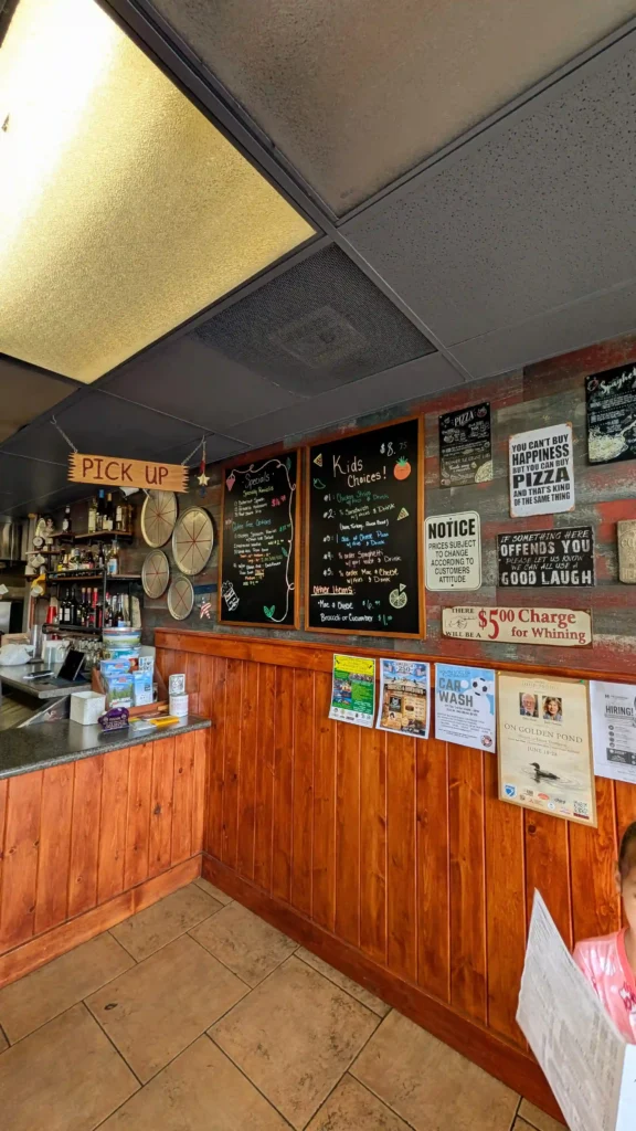 Front counter inside Maggio's Pizza in Big Bear Lake featuring wood paneling, chalkboard specials, and pickup area.