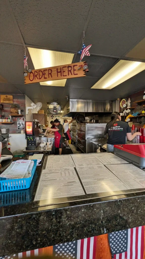 Open kitchen at Maggio's Pizza with staff preparing fresh pizzas during a busy dinner rush.