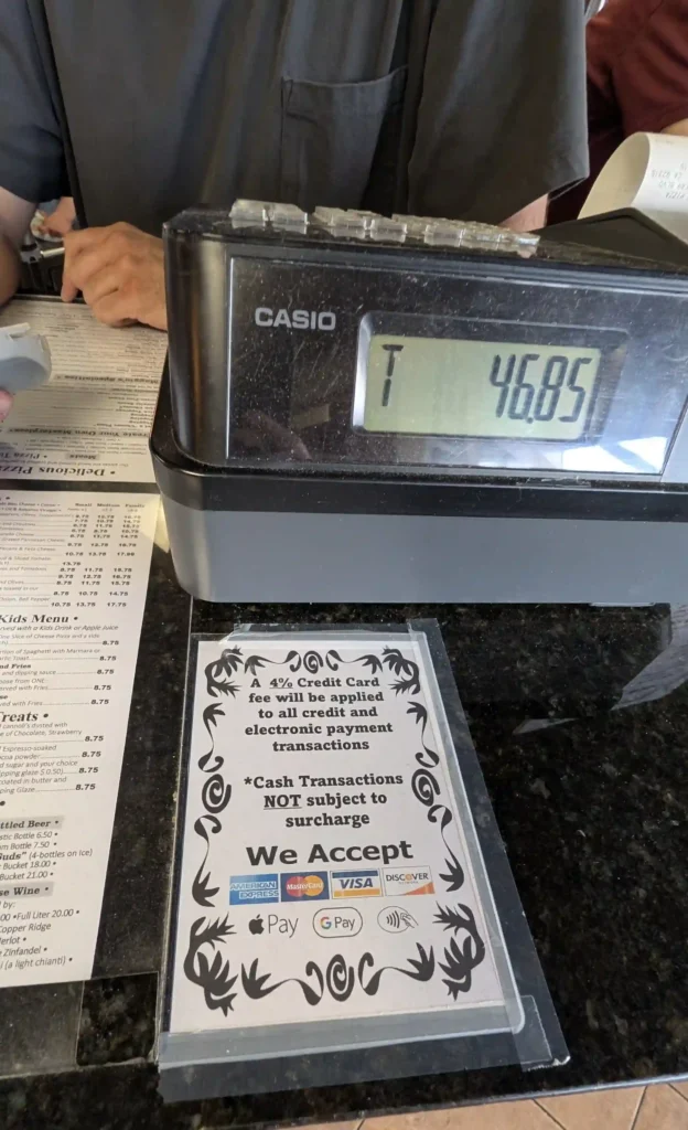 Credit card payment station at Maggio's Pizza displaying a 4 percent surcharge notice for electronic payments.
