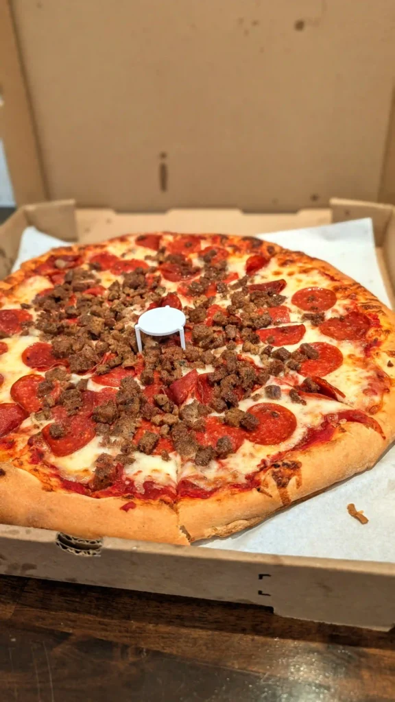 Close-up of pepperoni and homemade Italian sausage pizza showing thick toppings, melted cheese, and golden crust.